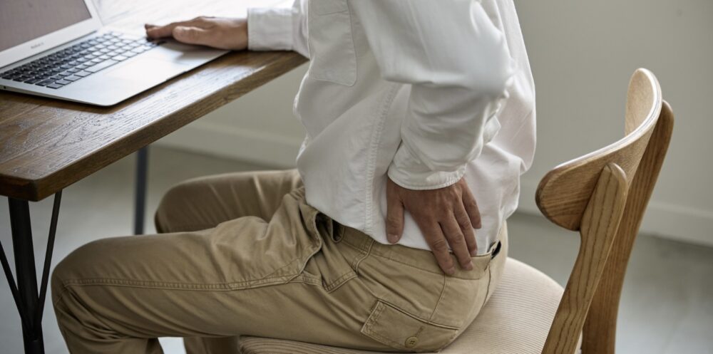 Person sitting at an office desk with back pain